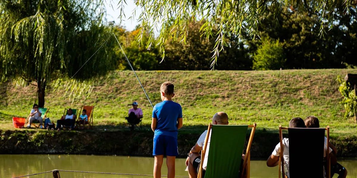 Young boy fishing from the bank of a calm park pond