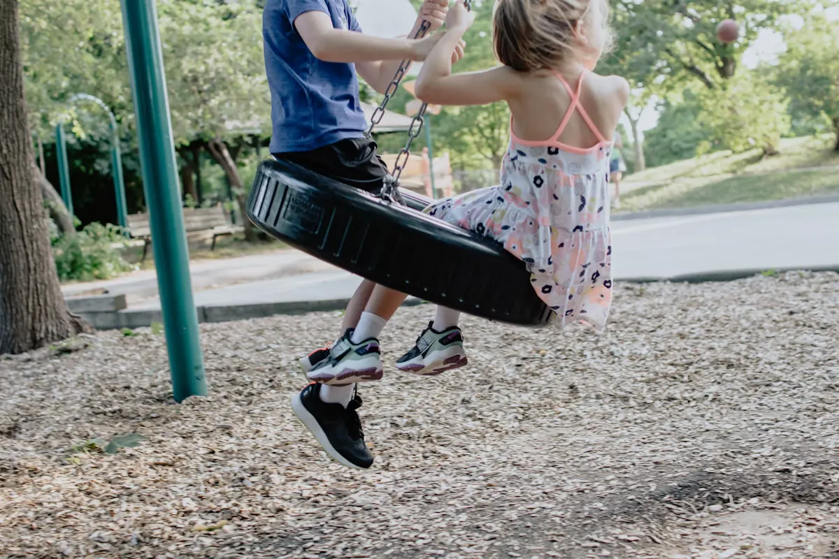 Child on a swing in a large outdoor park on a sunny afternoon