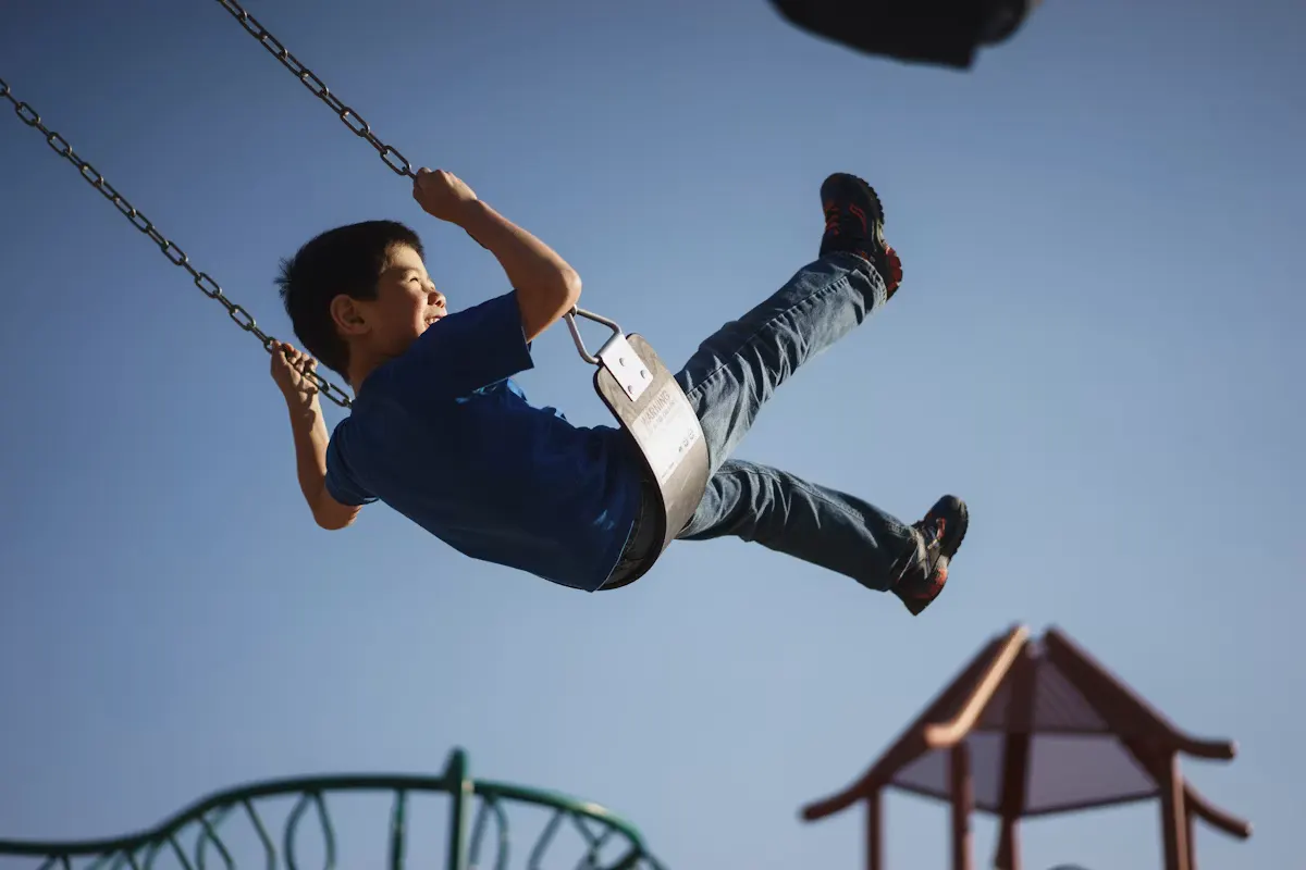 Child playing on a swing at a park on a sunny day
