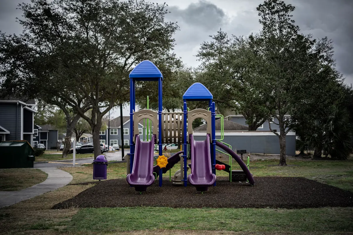 Colorful playground with slides and climbing structures surrounded by trees