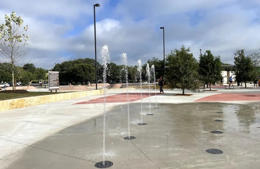Playground and splash pad shaded by oaks at San Gabriel Park — Georgetown, TX
