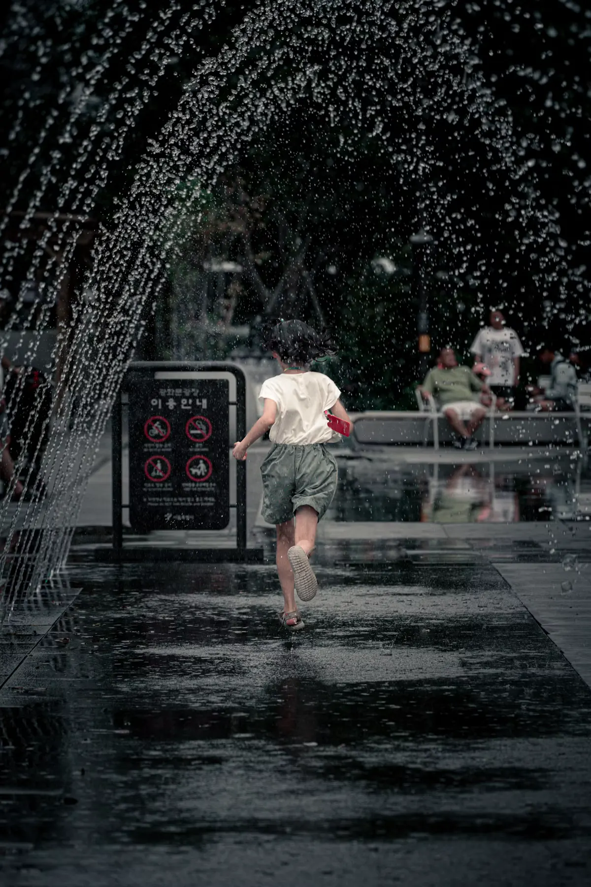 Child running through a water fountain arch at a spray ground